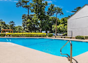 Thumbnail 9 of 20 - a swimming pool with a building and trees in the background